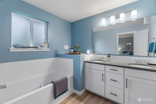 bathroom with double vanity, a bathtub, and hardwood / wood-style floors