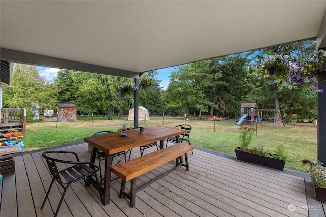 wooden terrace featuring a shed, a lawn, and a playground