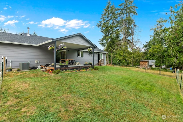 rear view of property featuring central AC unit, a yard, and a deck