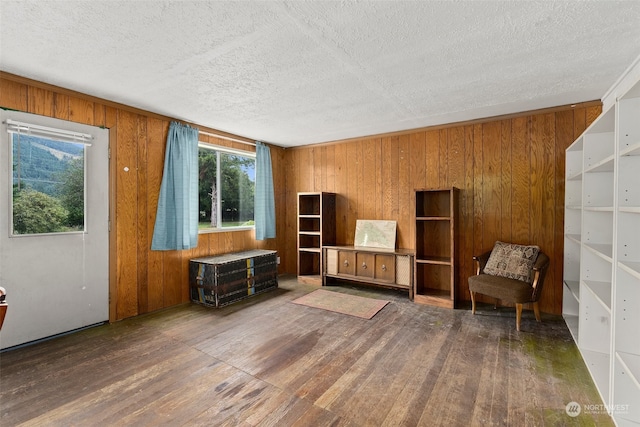 unfurnished room featuring dark wood-type flooring, a textured ceiling, and wooden walls