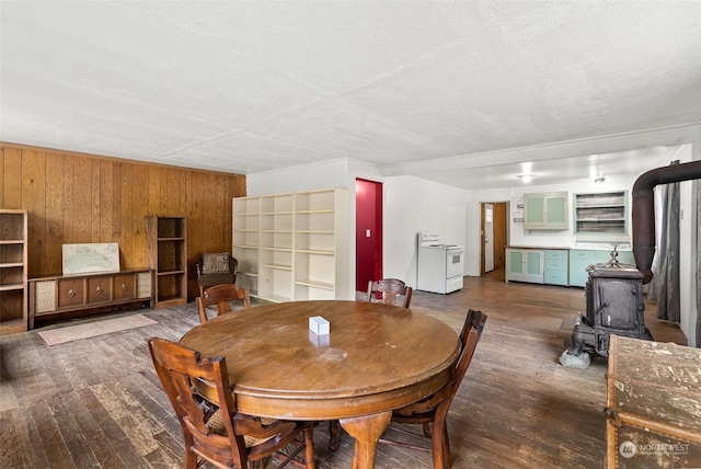 dining room with wooden walls, a wood stove, hardwood / wood-style floors, and a textured ceiling