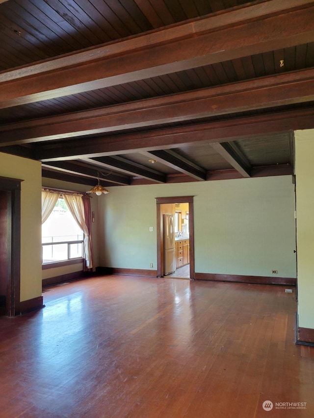 unfurnished room featuring beamed ceiling and hardwood / wood-style floors