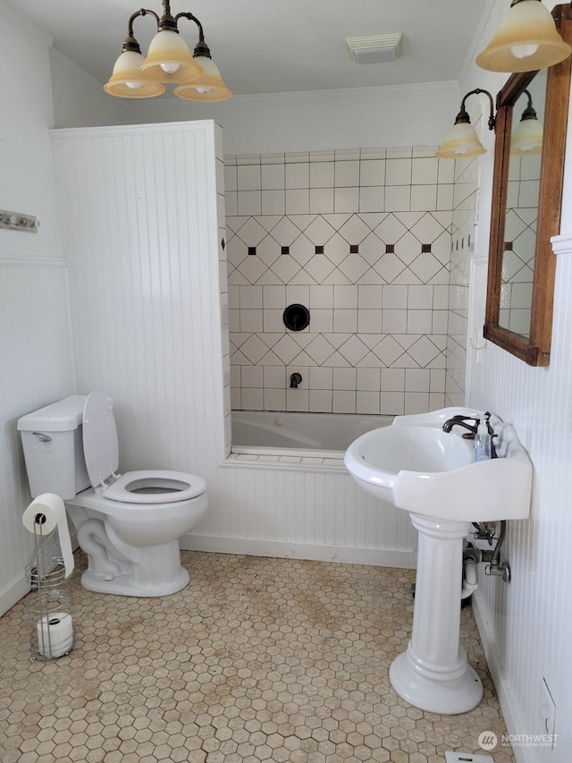 bathroom with a chandelier, ornamental molding, toilet, and tiled shower / bath combo