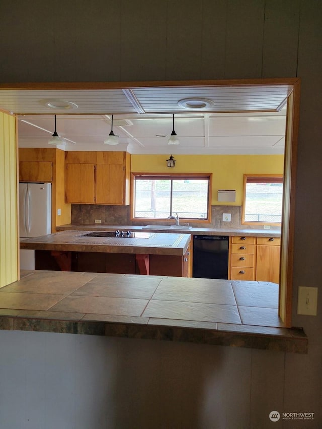 kitchen with tile counters, sink, decorative backsplash, and black appliances