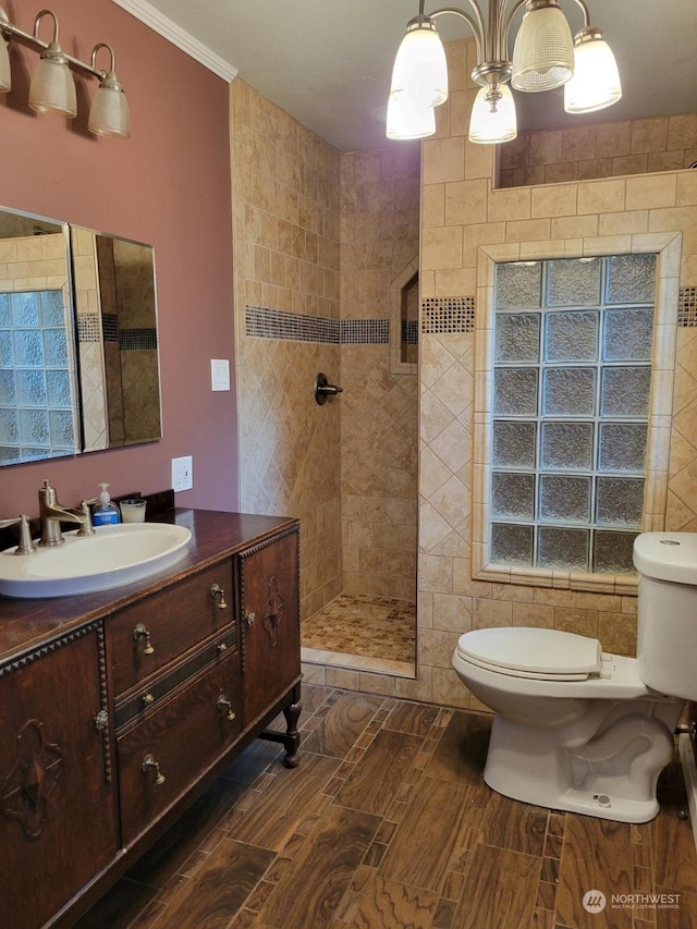 bathroom featuring vanity, crown molding, toilet, and tiled shower