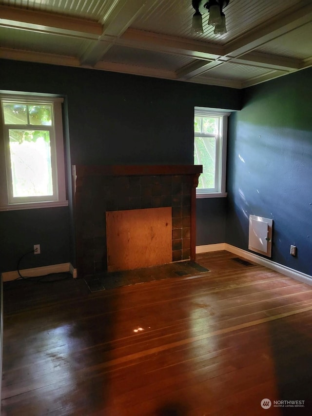 unfurnished living room with coffered ceiling, beam ceiling, a fireplace, and wood-type flooring