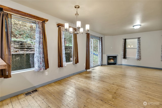 unfurnished living room with a chandelier and light hardwood / wood-style floors