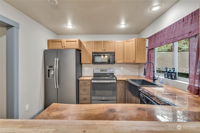 kitchen featuring sink, stainless steel appliances, butcher block countertops, kitchen peninsula, and light brown cabinetry