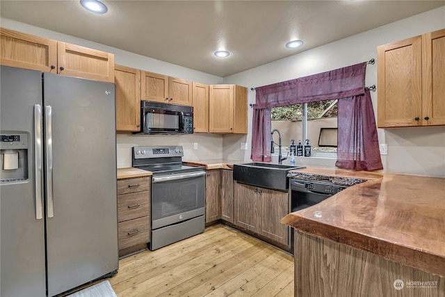 kitchen with light brown cabinetry, sink, stainless steel appliances, and light hardwood / wood-style flooring