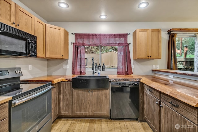 kitchen with black appliances, wood counters, plenty of natural light, and sink