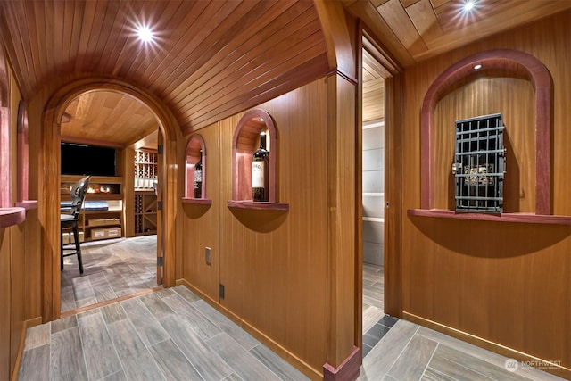 corridor with wood ceiling, vaulted ceiling, and wood walls