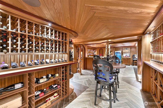 wine area featuring parquet floors, wood ceiling, and wooden walls