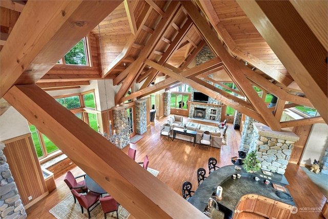 living room featuring hardwood / wood-style flooring, high vaulted ceiling, a fireplace, wooden ceiling, and beamed ceiling