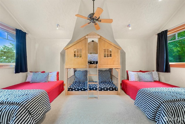 carpeted bedroom featuring multiple windows, lofted ceiling, and a textured ceiling