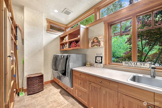 clothes washing area featuring separate washer and dryer, sink, plenty of natural light, and cabinets