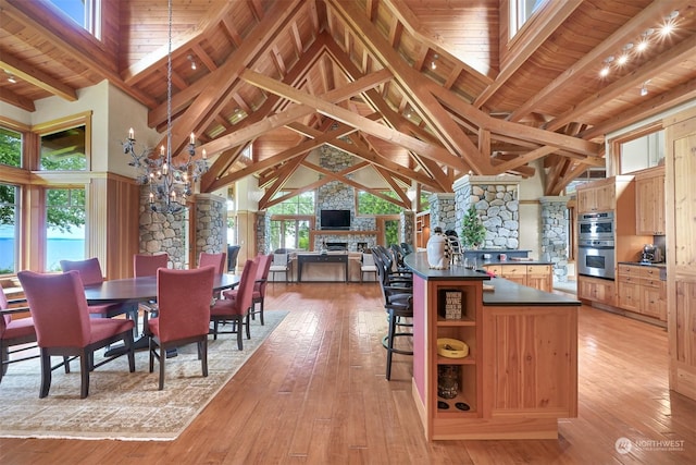 kitchen with double oven, beamed ceiling, light hardwood / wood-style floors, a healthy amount of sunlight, and a chandelier