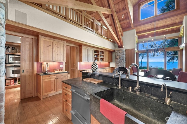 kitchen featuring dark stone countertops, light hardwood / wood-style floors, a high ceiling, and appliances with stainless steel finishes