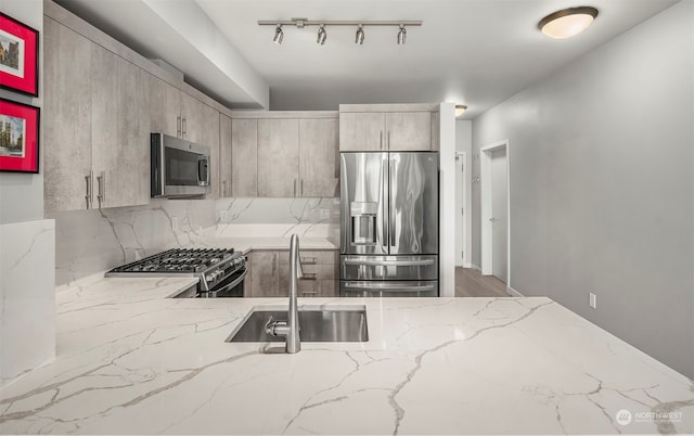 kitchen featuring appliances with stainless steel finishes, tasteful backsplash, sink, and light stone countertops