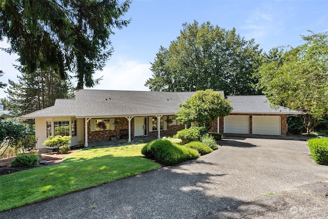 single story home featuring a porch, a front yard, and a garage