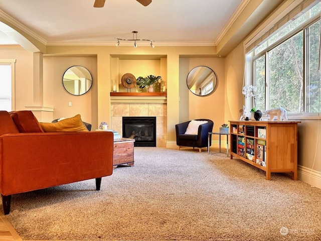 living room featuring carpet flooring, a fireplace, ceiling fan, and crown molding