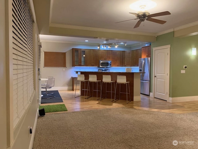 kitchen featuring stainless steel appliances, crown molding, and light wood-type flooring