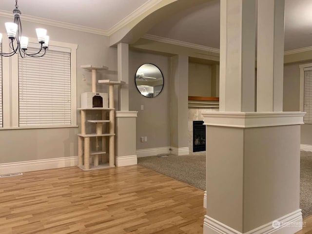 unfurnished living room with an inviting chandelier, light hardwood / wood-style flooring, and ornamental molding