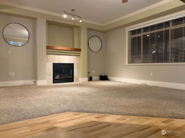 unfurnished living room featuring a fireplace, crown molding, and carpet