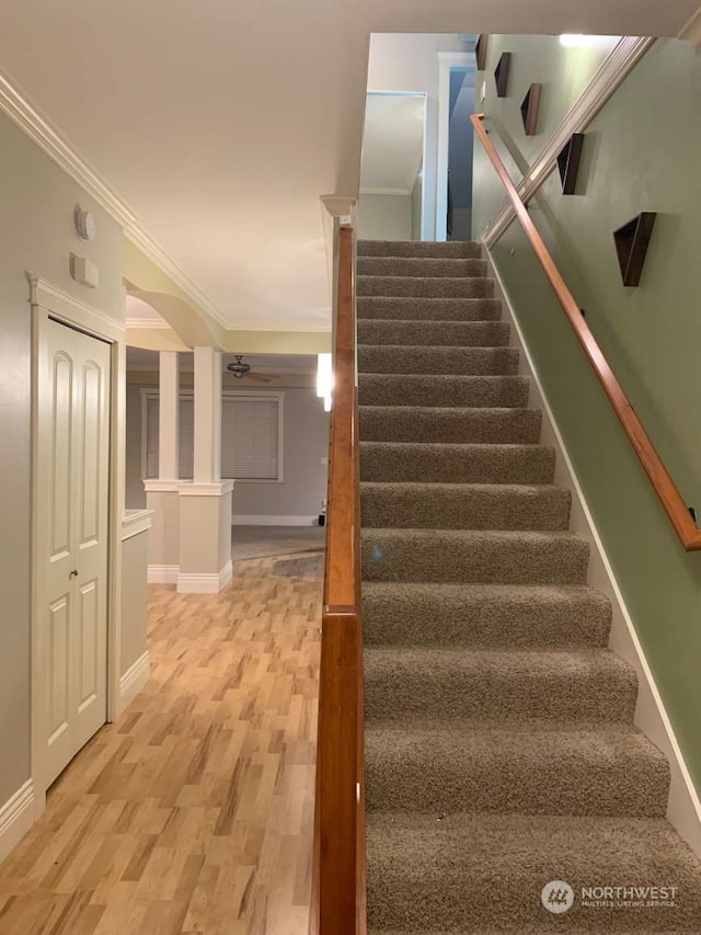 stairway with light hardwood / wood-style floors and ornamental molding