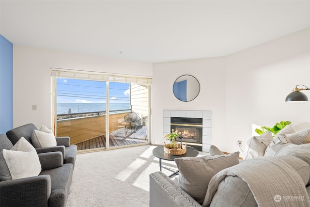 carpeted living room with a tile fireplace and a water view