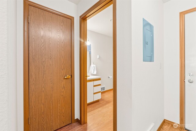 hallway with electric panel and light wood-type flooring