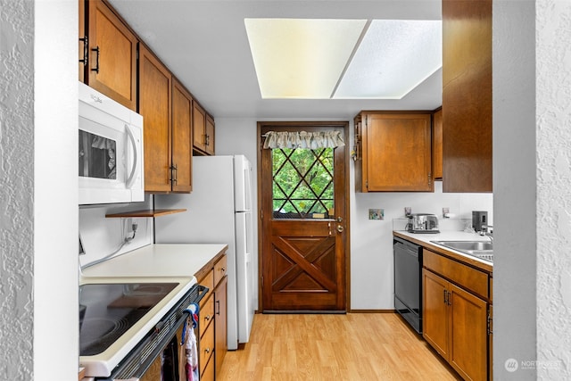 kitchen with electric stove, black dishwasher, sink, and light wood-type flooring