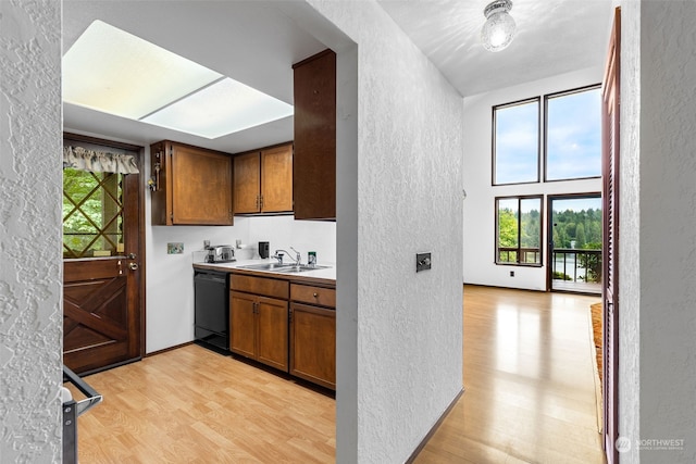 kitchen with sink, black dishwasher, and light wood-type flooring