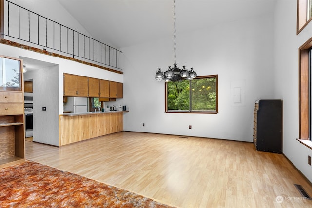 kitchen with an inviting chandelier, high vaulted ceiling, white fridge, pendant lighting, and stove