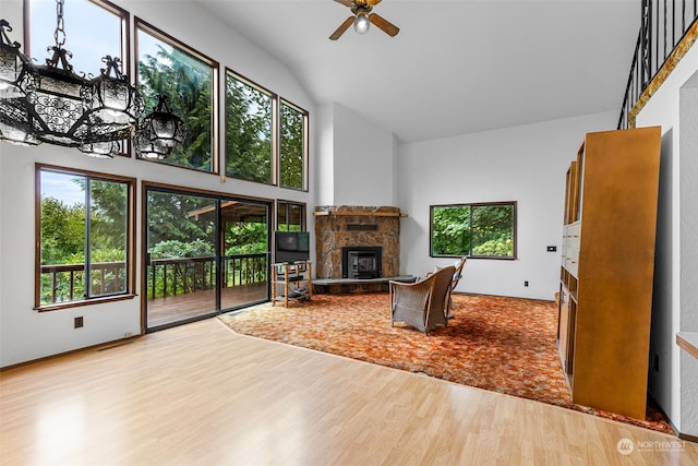 living room featuring light hardwood / wood-style flooring, a fireplace, high vaulted ceiling, and ceiling fan