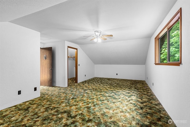 additional living space featuring a textured ceiling, carpet floors, ceiling fan, and vaulted ceiling