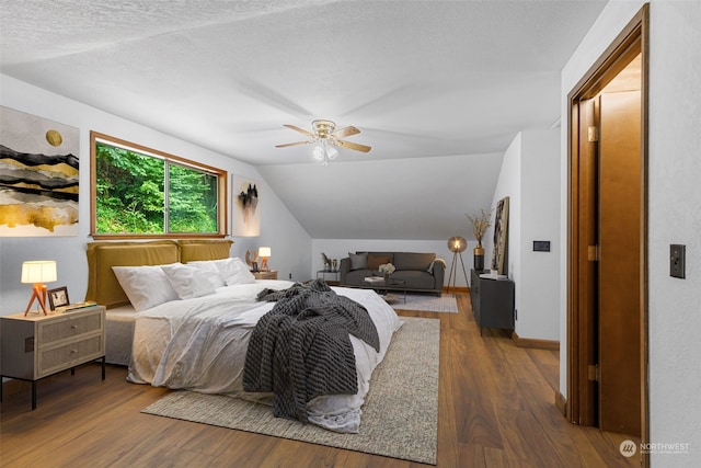 bedroom with ceiling fan, lofted ceiling, a textured ceiling, and dark hardwood / wood-style flooring