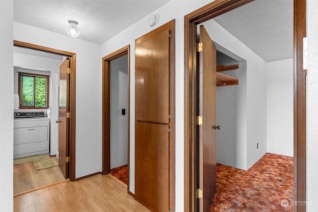 corridor with washer / clothes dryer, a textured ceiling, and light hardwood / wood-style floors