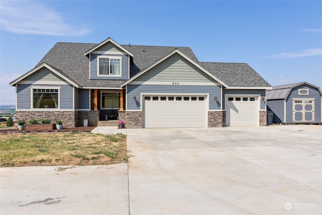 craftsman house with an outbuilding, a garage, a storage shed, a shingled roof, and driveway