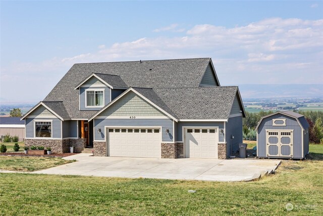 view of front of property featuring a front yard, a garage, and a shed