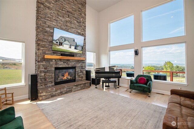 living room featuring a fireplace, light wood-type flooring, and a high ceiling