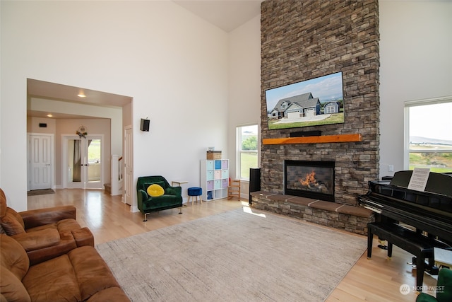 living room featuring a towering ceiling, light hardwood / wood-style flooring, and a healthy amount of sunlight