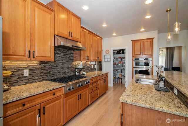 kitchen with light stone countertops, light hardwood / wood-style floors, hanging light fixtures, and decorative backsplash