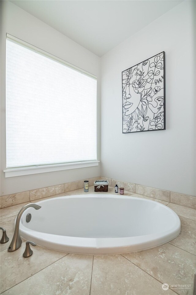 bathroom with tiled tub and a wealth of natural light