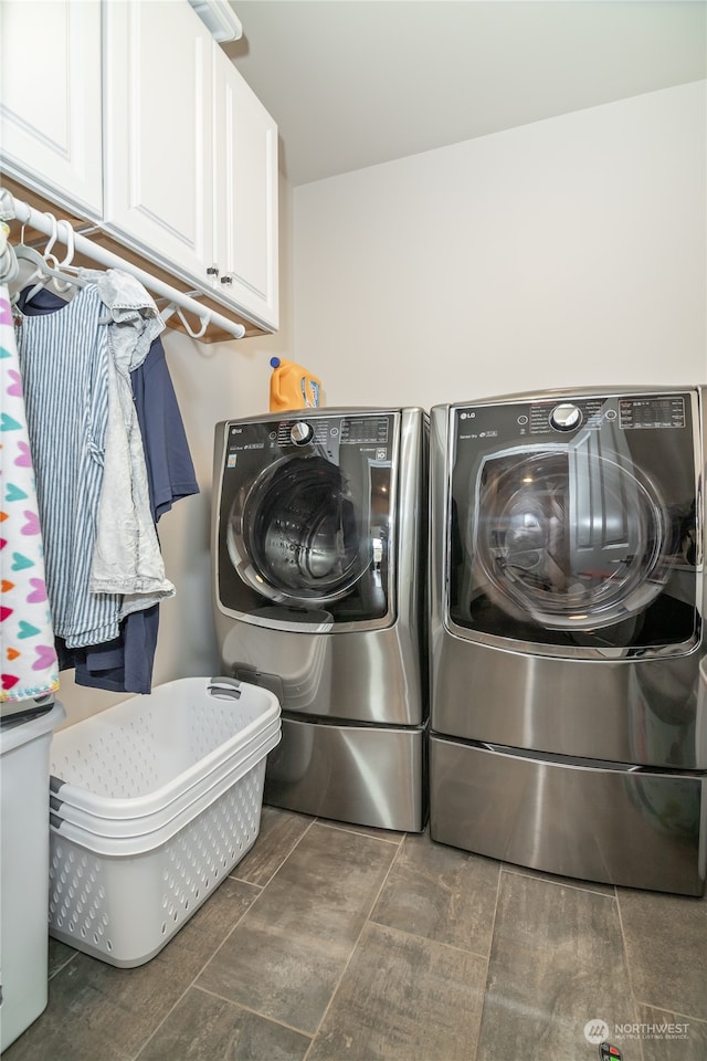 washroom featuring cabinets, washing machine and dryer, and dark tile patterned floors