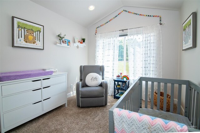 carpeted bedroom featuring a crib and vaulted ceiling