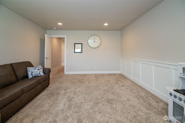 carpeted living room featuring a wainscoted wall, recessed lighting, and a decorative wall