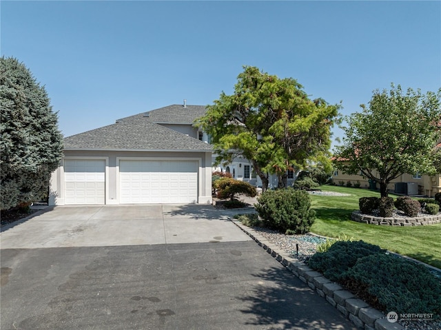 view of front of house with a garage, concrete driveway, roof with shingles, a front yard, and stucco siding