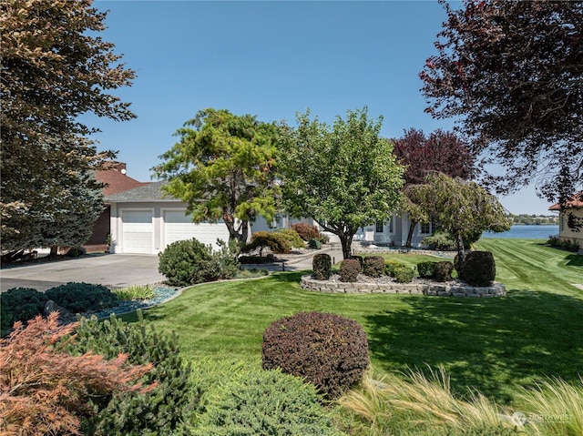 obstructed view of property with an attached garage, concrete driveway, and a front yard