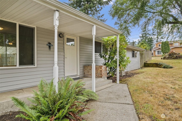 view of exterior entry with a yard and a porch