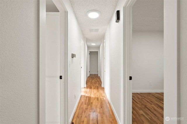 hall featuring wood-type flooring and a textured ceiling